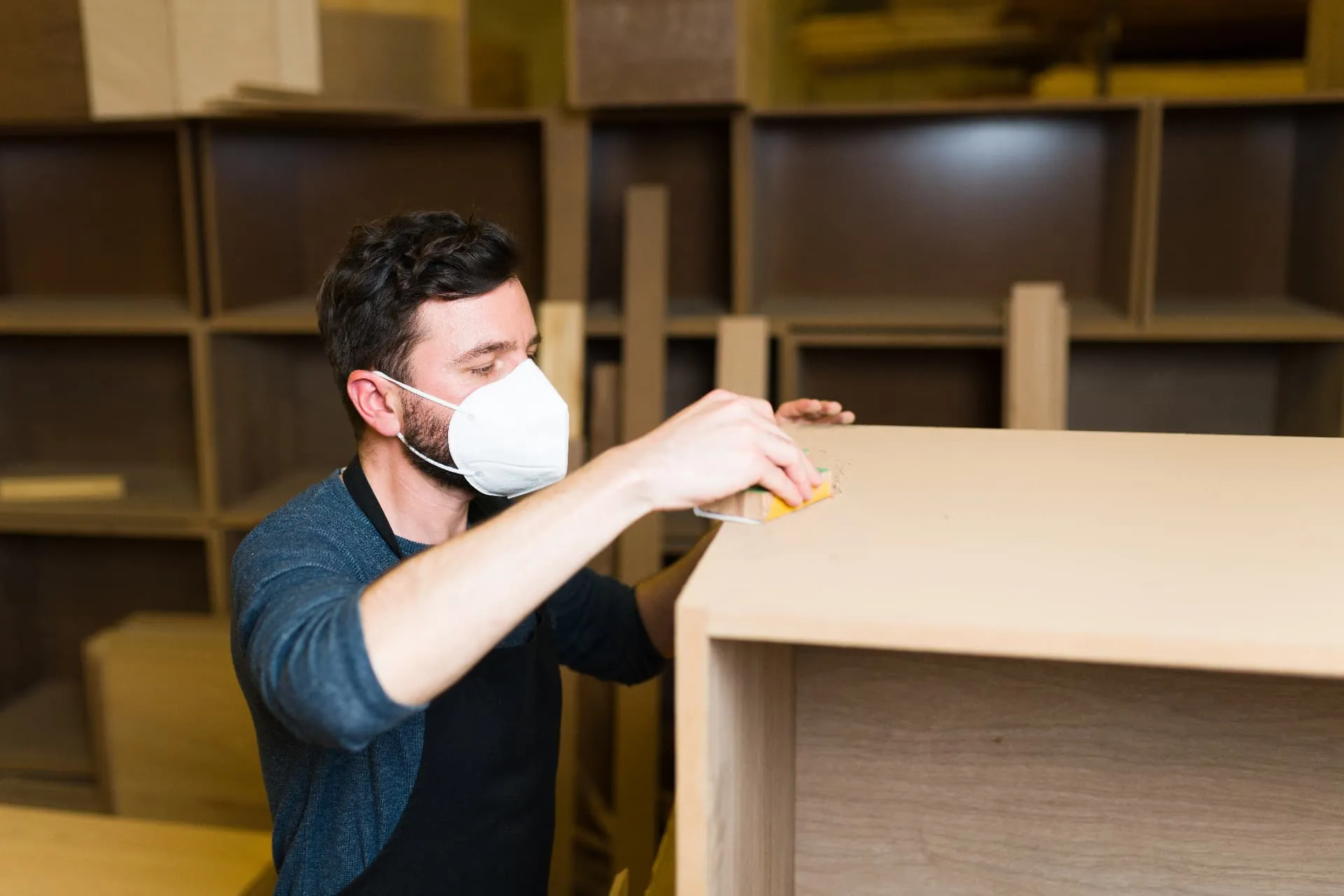A craftsman hand-sanding a piece of made-to-measure furniture in the workshop