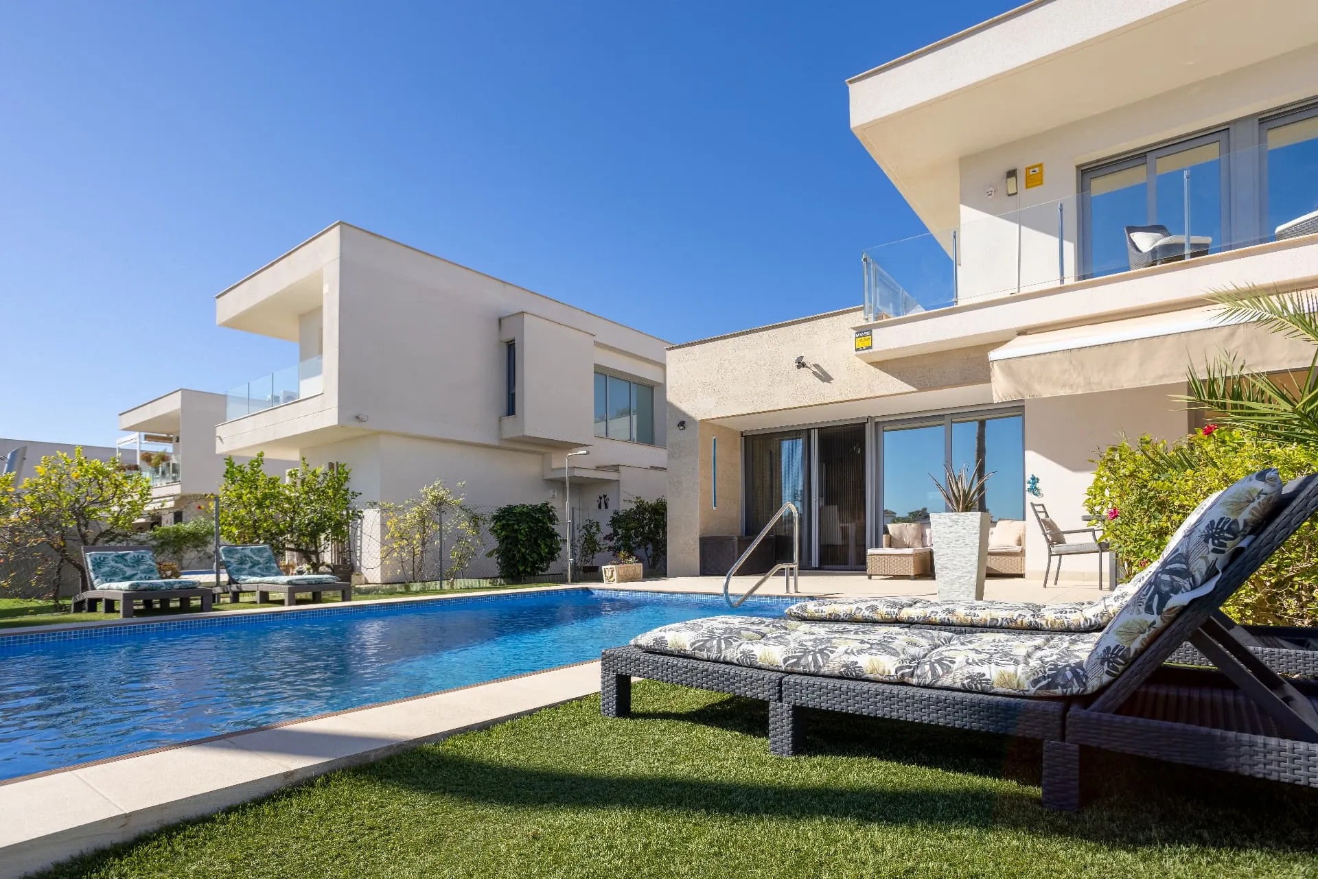 A villa pool terrace with sun loungers and outdoor seating under bright Algarve light