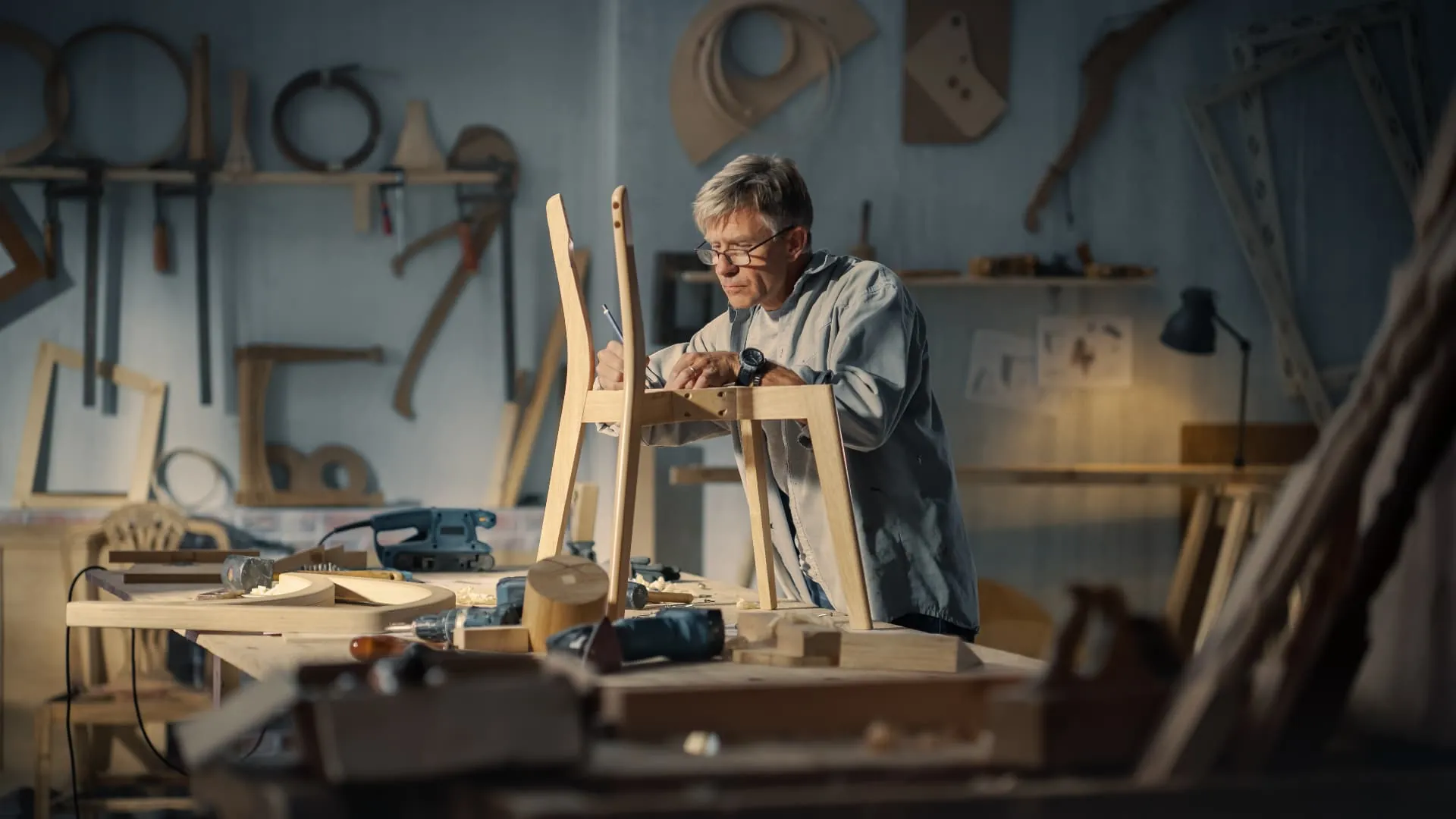 A craftsman marking out a wooden chair frame at the workbench