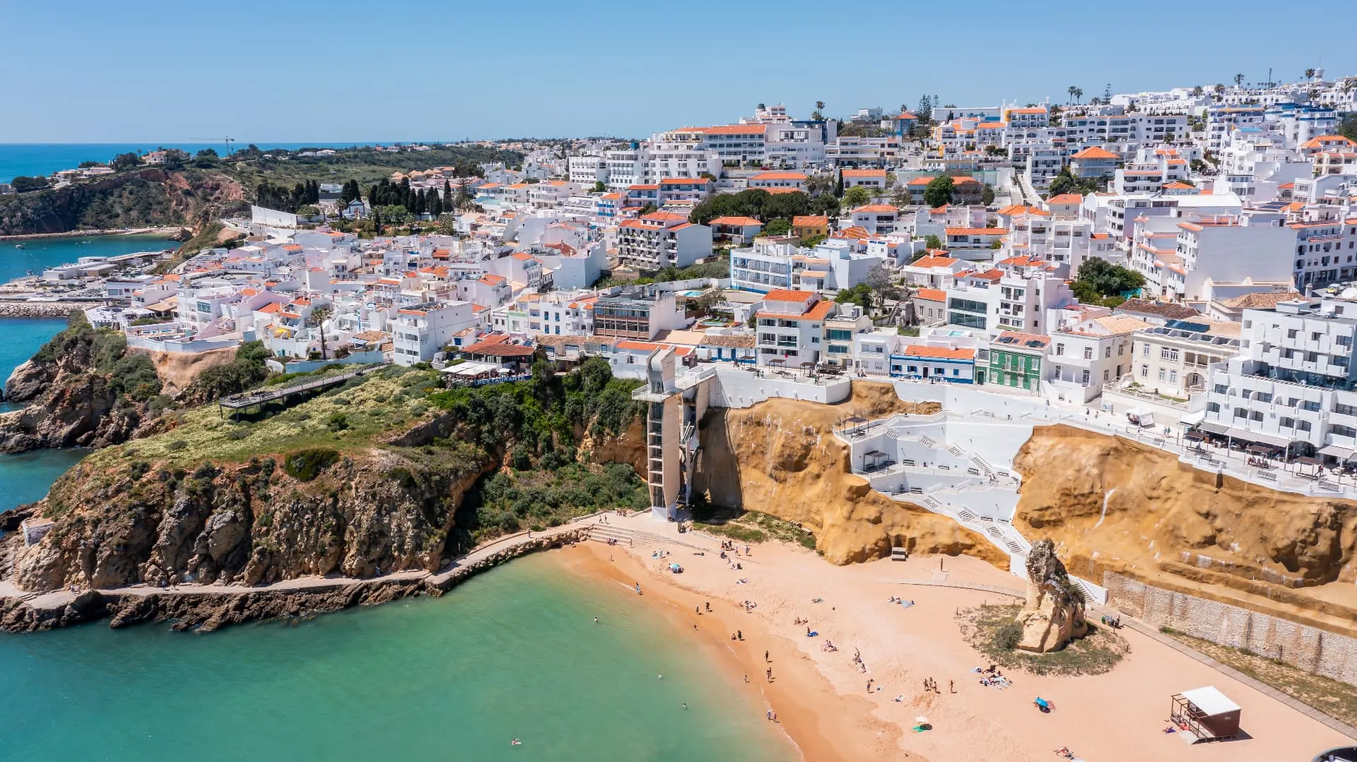 Albufeira's white coastal town above ochre cliffs, a sandy beach and turquoise water