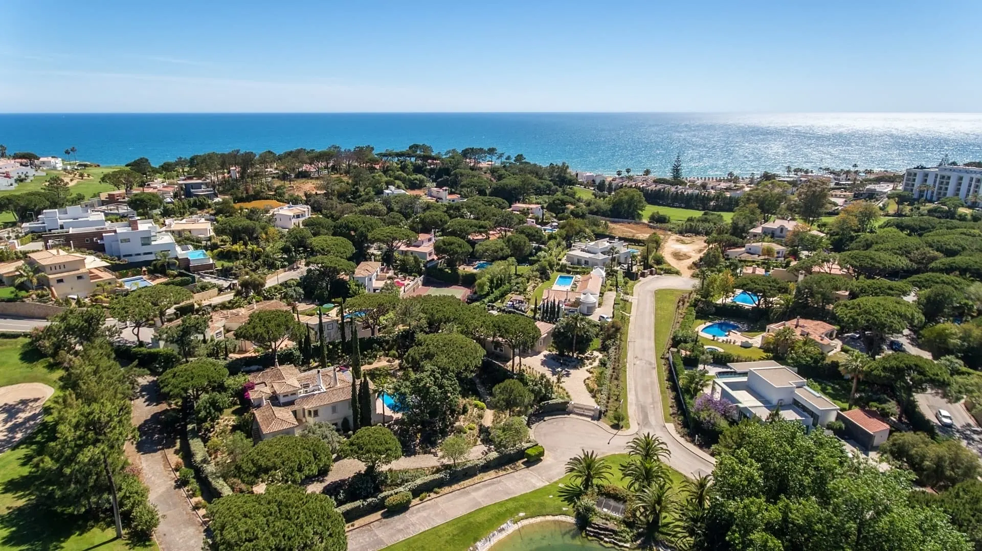 Aerial view of villas and greenery along the coast near Almancil, with the sea beyond