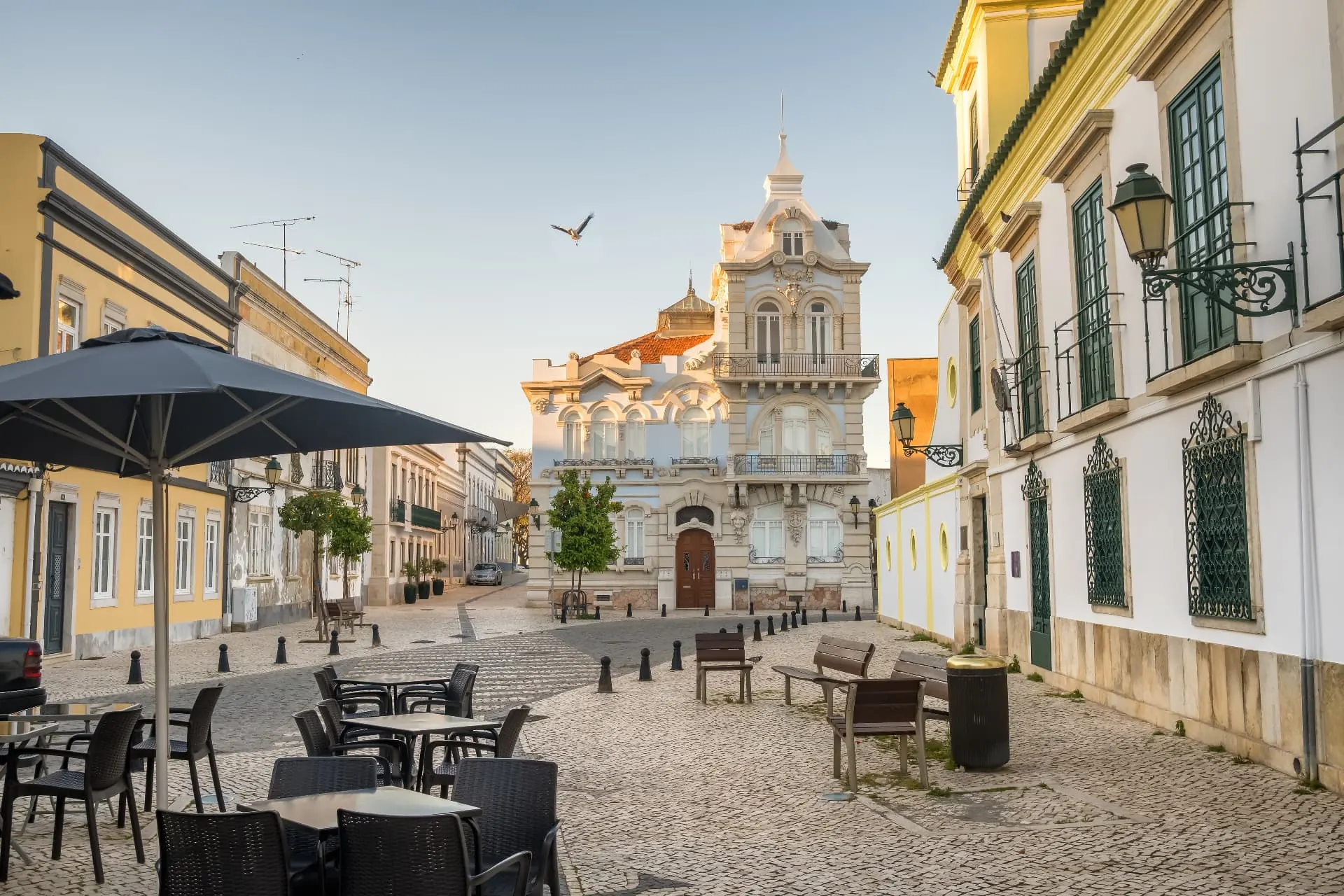 Historic square in Faro with pale façades, outdoor seating and cobbled paving