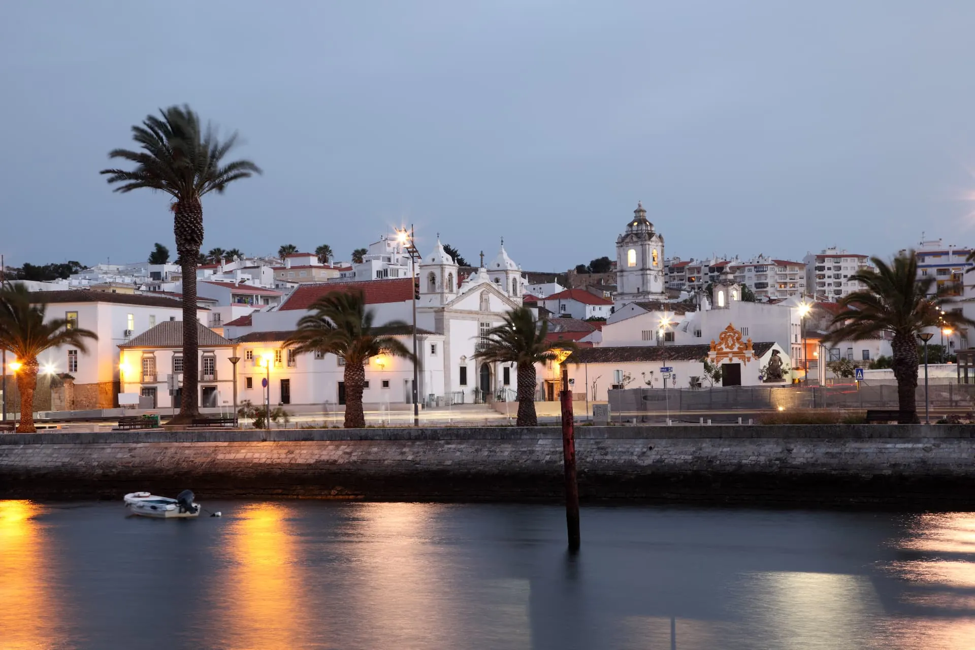 Lagos waterfront at dusk, with palm trees, church towers and their reflections in the water